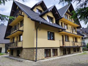 a yellow building with a black roof at Pokoje Gościnne "Tęcza" in Zakopane