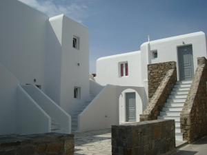 una casa blanca con escaleras y un cielo azul en Elena Studios & Suites, en Ornos
