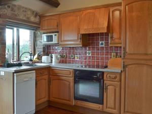 a kitchen with wooden cabinets and a stove top oven at Brandy's in Colyton