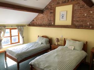 a bedroom with two beds and a brick wall at The Drift House in Coddington