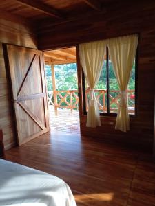 a bedroom with a bed and two windows and a wooden floor at Cabaña tolle Vista in Savegre