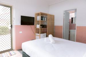 a bedroom with a white bed and a tv at Black Swan Waterfront Motel in Swansea