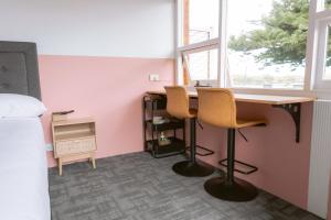 a room with a desk with two chairs and a bed at Black Swan Waterfront Motel in Swansea