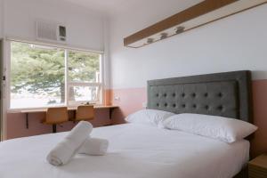 Schlafzimmer mit einem Bett mit weißer Bettwäsche und einem Fenster in der Unterkunft Black Swan Waterfront Motel in Swansea