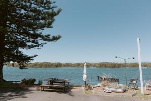 a picnic table and a boat on a lake at Black Swan Waterfront Motel in Swansea