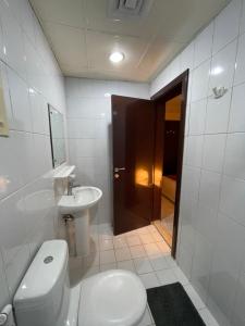 a white bathroom with a toilet and a sink at Pharaohs Inn Deira Hostel in Dubai