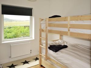 a bedroom with two bunk beds and a window at The Seashells in Brancaster
