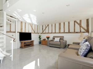 a living room with two couches and a flat screen tv at Tatters Barn in Bradwell