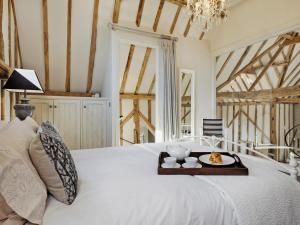 a white bed with a tray of food on it at Tatters Barn in Bradwell