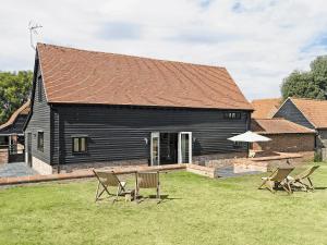 a black house with chairs in front of it at Tatters Barn in Bradwell