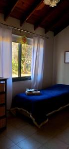 1 dormitorio con cama azul y ventana en Aldea de Montaña ,La Pichuca en Carpintería