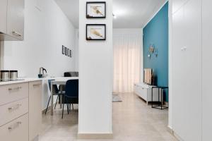 cocina y comedor con armarios blancos y paredes azules en Jòia Holiday Home, en Crotone