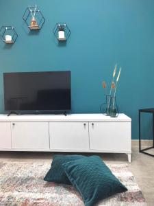 a living room with a white dresser with a tv on a blue wall at Jòia Holiday Home in Crotone