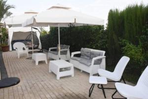 eine Terrasse mit weißen Stühlen und einem Sonnenschirm in der Unterkunft Sounds Suite for families in Migdal