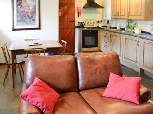a brown couch with two pink pillows in a kitchen at Piglet Cottage in Elsdon
