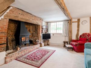 a living room with a brick fireplace and a red couch at The Croft - 28243 in Sible Hedingham