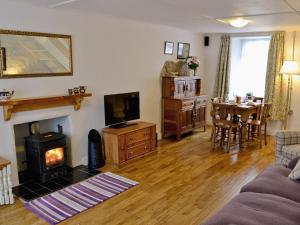 a living room with a fireplace and a living room with a table at Jackdaw Cottage in Baycliff