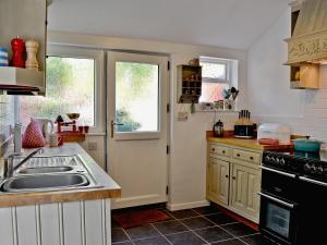 uma cozinha com um lavatório e um fogão em Jackdaw Cottage em Baycliff