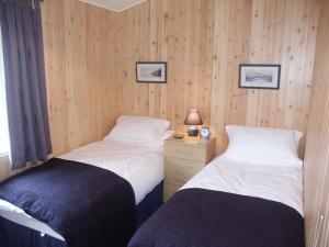 Habitación con 2 camas y paredes revestidas de madera. en Amber Nook en Tirril