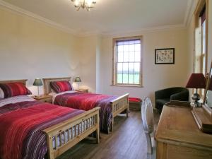 a bedroom with two beds and a desk and a window at Rascal Wood in Holme upon Spalding Moor