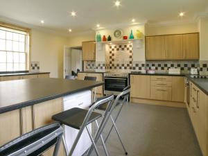a large kitchen with wooden cabinets and bar stools at Rascal Wood in Holme upon Spalding Moor