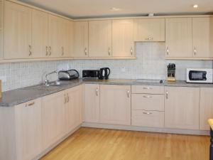 uma cozinha com armários brancos e um lavatório em 12 Maritime House em West Bay