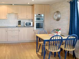 a kitchen with a table and chairs and a clock on the wall at 12 Maritime House in West Bay