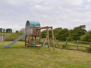 a playground with a slide in the grass at Millers Rest in Poundstock