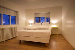 a white bed in a room with two windows at Draflastadir Guesthouse in Draflastaðir