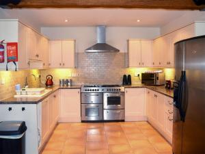 a kitchen with white cabinets and a stainless steel stove at Kestrel Barn - Cul in Sculthorpe
