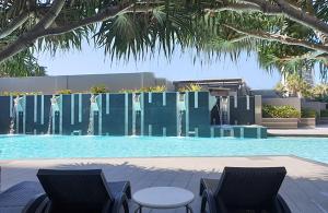 a swimming pool with two chairs and a fountain at Sealuxe - Surfers Paradise Central -- Ocean View Deluxe Residences in Gold Coast