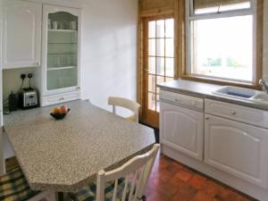 a kitchen with white cabinets and a counter top at Middledrift Cottage in Brora