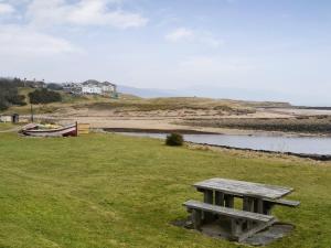 a picnic table sitting in the grass near a body of water at Middledrift Cottage in Brora