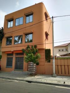 um edifício laranja com uma árvore em frente em Studio Assiba 1 em Cotonou