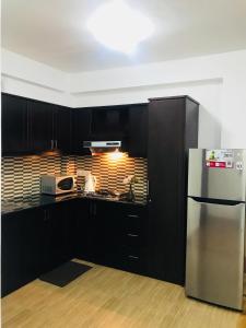 cocina con armarios negros y nevera de acero inoxidable en City Apartment’s Nuwara Eliya en Nuwara Eliya