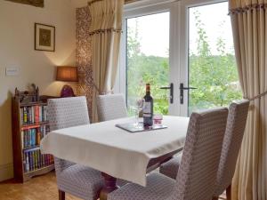a dining room table with a bottle of wine and chairs at Wisteria Cottage in Skirpenbeck