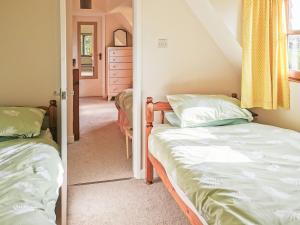 a bedroom with two twin beds and a mirror at Violet Cottage in Dudbridge