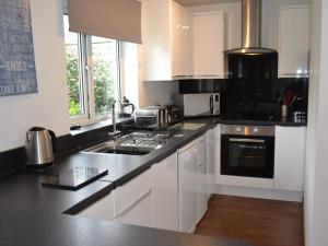 a kitchen with white cabinets and a black counter top at Summer Breeze in St Austell