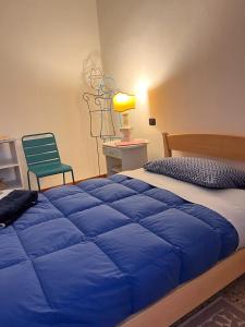 sypialnia z niebieskim łóżkiem i zielonym krzesłem w obiekcie B&B Camelia w mieście Città di Castello