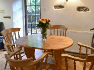 una mesa de madera con un jarrón de flores. en Mill Cottage, en Buckfastleigh