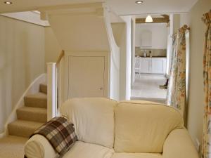 un sofá blanco en una sala de estar con escaleras en The Bothy, en Laverton