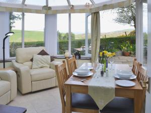 a living room with a table and chairs and windows at Nells Cottage in Askam in Furness