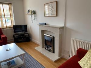 a living room with a fireplace and a tv at Bayeux Cottage in East Budleigh
