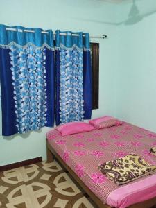 a bedroom with a bed and blue curtains at UK homestay in Malvan