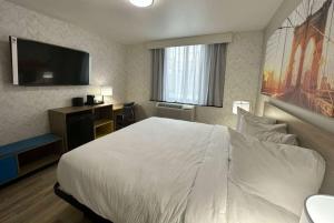 a hotel room with a white bed and a flat screen tv at Days Inn by Wyndham Brooklyn Eastern Parkway in Brooklyn