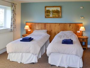 two beds in a room with blue towels on them at Barleycorn in Holwell