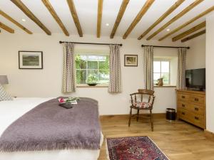 a bedroom with a bed and a chair and a television at The Calf Shed-ukc2113 in Royal Wootton Bassett
