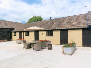 a building with a patio with tables and an umbrella at The Calf Shed-ukc2113 in Royal Wootton Bassett