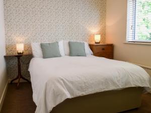 a bedroom with a large white bed with two lamps at Cobden House in Lakenheath