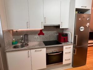 cocina con armarios blancos y nevera de acero inoxidable en Loft con PARKING "Hygge Urbano Coruña", en A Coruña